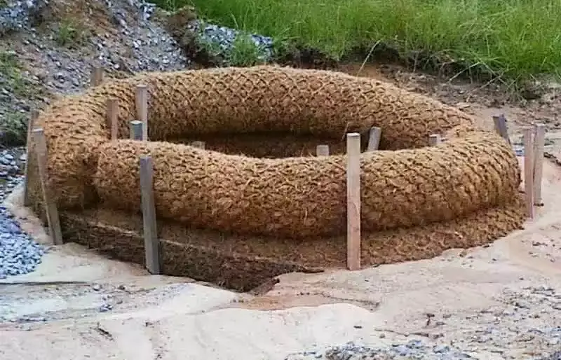 Biodegradable coir logs installed for erosion control, featuring natural coconut fiber construction secured with wooden stakes to stabilize soil and prevent sediment runoff in environmentally sensitive areas